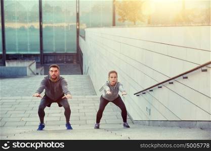 fitness, sport, people, exercising and lifestyle concept - couple doing squats on city street stairs. couple doing squats on city street stairs