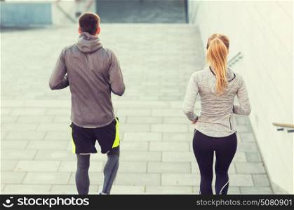 fitness, sport, people, exercising and lifestyle concept - couple running downstairs on city stairs. couple running downstairs on city stairs