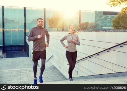 fitness, sport, people, exercising and lifestyle concept - happy couple running upstairs on city stairs. happy couple running upstairs on city stairs