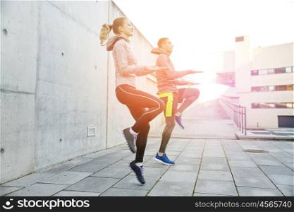 fitness, sport, people, exercising and lifestyle concept - happy man and woman jumping outdoors