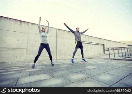 fitness, sport, people, exercising and lifestyle concept - happy man and woman jumping outdoors. happy man and woman jumping outdoors