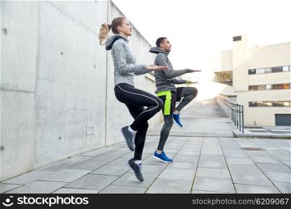 fitness, sport, people, exercising and lifestyle concept - happy man and woman jumping outdoors