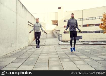 fitness, sport, people, exercising and lifestyle concept - man and woman skipping with jump rope outdoors. man and woman exercising with jump-rope outdoors