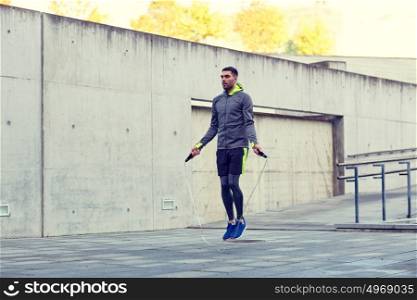 fitness, sport, people, exercising and lifestyle concept - man skipping with jump rope outdoors. man exercising with jump-rope outdoors