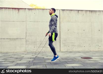 fitness, sport, people, exercising and lifestyle concept - man skipping with jump rope outdoors. man exercising with jump-rope outdoors