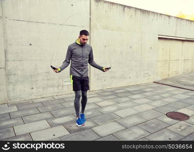 fitness, sport, people, exercising and lifestyle concept - man skipping with jump rope outdoors. man exercising with jump-rope outdoors