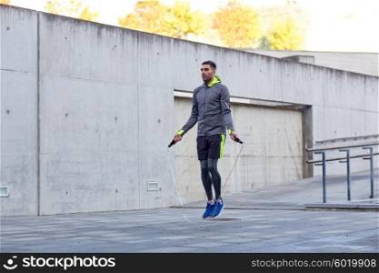 fitness, sport, people, exercising and lifestyle concept - man skipping with jump rope outdoors
