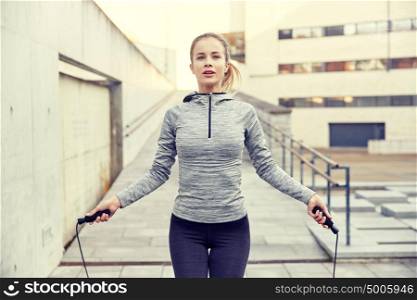 fitness, sport, people, exercising and lifestyle concept - woman skipping with jump rope outdoors. woman exercising with jump-rope outdoors