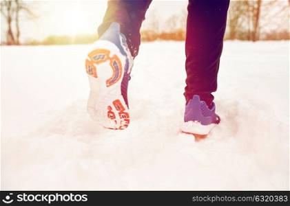 fitness, sport, people, footwear and healthy lifestyle concept - close up of male feet running along winter road and snow. close up of feet running along snowy winter road