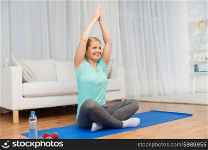 fitness, sport, people, meditation and yoga concept - woman meditating in lotus pose on mat at home