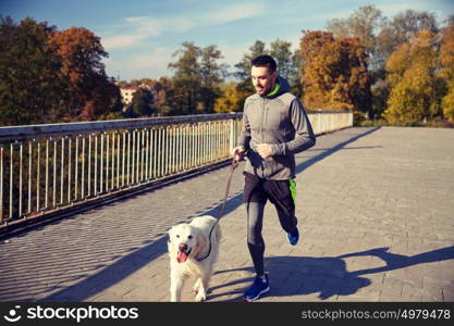 fitness, sport, people, pets and jogging concept - happy man with labrador retriever dog running outdoors. happy man with labrador dog running outdoors