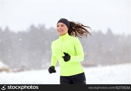 fitness, sport, people, season and healthy lifestyle concept - happy woman running along snow covered winter road. happy woman running along snow covered winter road