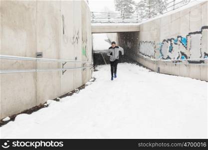 fitness, sport, people, season and healthy lifestyle concept - young man running out of pedestrian subway tunnel in winter