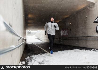 fitness, sport, people, season and healthy lifestyle concept - young man running along pedestrian subway tunnel in winter
