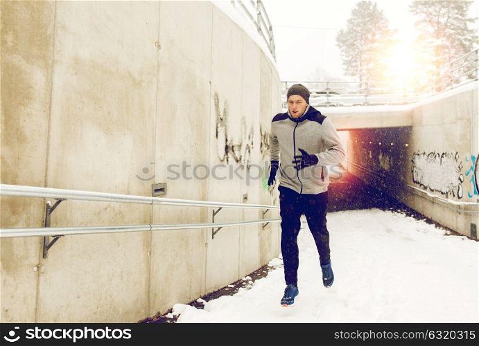 fitness, sport, people, season and healthy lifestyle concept - young man running out of pedestrian subway tunnel in winter. man running out of subway tunnel in winter