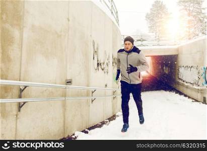 fitness, sport, people, season and healthy lifestyle concept - young man running out of pedestrian subway tunnel in winter. man running out of subway tunnel in winter
