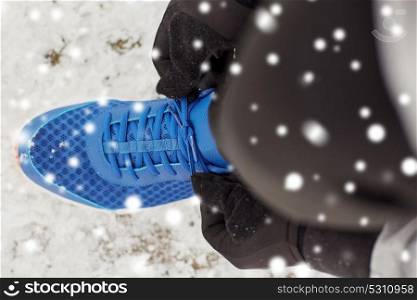 fitness, sport, people, sportswear and footwear concept - close up of man foot and hands tying shoe lace in winter outdoors. close up of man tying shoe lace in winter outdoors