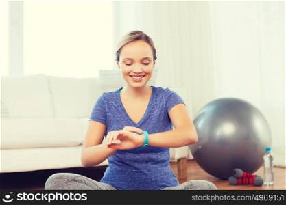 fitness, sport, people, technology and healthy lifestyle concept - happy woman with heart-rate watch exercising at home. happy woman with heart-rate watch exercising