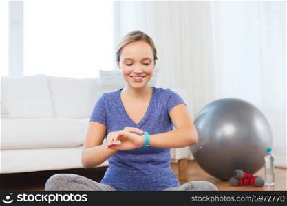 fitness, sport, people, technology and healthy lifestyle concept - happy woman with heart-rate watch exercising at home