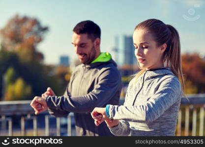 fitness, sport, people, technology and healthy lifestyle concept - smiling couple with heart-rate watch running over city highway bridge. couple running over city highway bridge