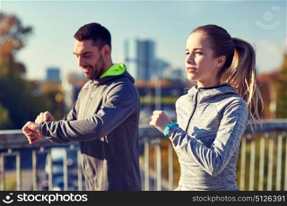 fitness, sport, people, technology and healthy lifestyle concept - smiling couple with heart-rate watch running over city highway bridge. couple running over city highway bridge