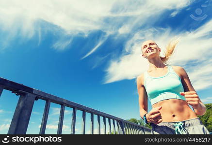 fitness, sport, people, technology and healthy lifestyle concept - smiling young woman with heart rate watch running outdoors