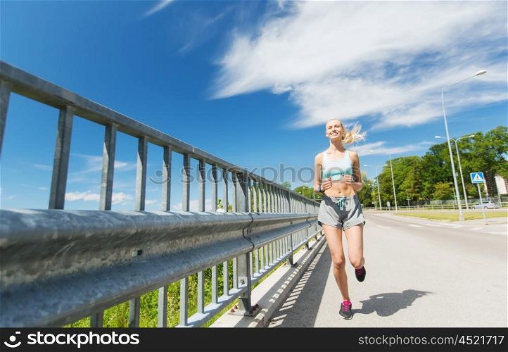 fitness, sport, people, technology and healthy lifestyle concept - smiling young woman with heart rate watch running outdoors