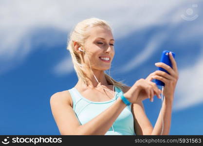 fitness, sport, people, technology and healthy lifestyle concept - smiling young woman with smartphone and earphones listening to music and exercising outdoors