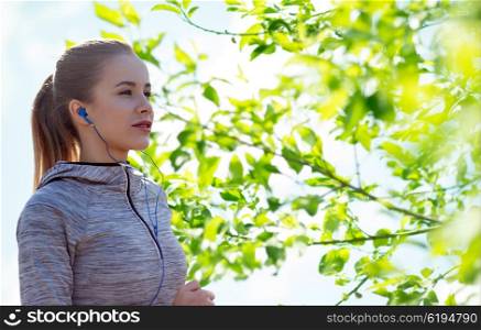 fitness, sport, people, technology and lifestyle concept - happy woman running and listening to music in earphones over green natural background
