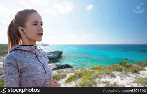 fitness, sport, people, technology and lifestyle concept - happy woman running and listening to music in earphones