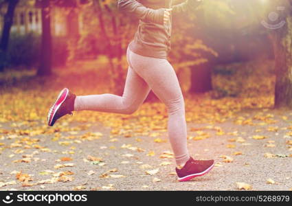 fitness, sport, people, wear and healthy lifestyle concept - close up of young woman running in autumn park. close up of young woman running in autumn park