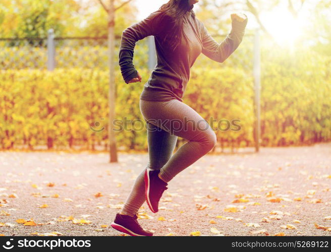 fitness, sport, people, wear and healthy lifestyle concept - close up of young woman running in autumn park. close up of young woman running in autumn park