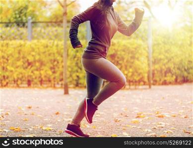 fitness, sport, people, wear and healthy lifestyle concept - close up of young woman running in autumn park. close up of young woman running in autumn park