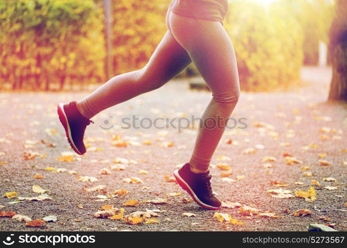 fitness, sport, people, wear and healthy lifestyle concept - close up of young woman running in autumn park. close up of young woman running in autumn park