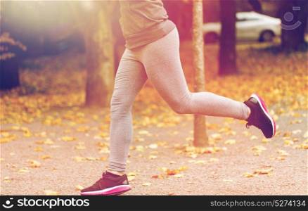 fitness, sport, people, wear and healthy lifestyle concept - close up of young woman running in autumn park. close up of young woman running in autumn park