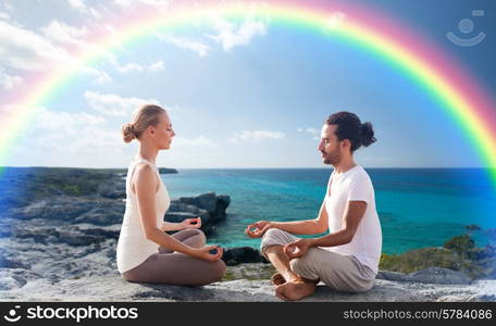 fitness, sport, people, yoga and lifestyle concept - happy couple meditating in lotus pose on summer beach