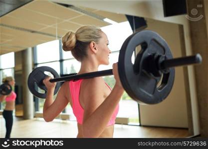 fitness, sport, powerlifting and people concept - sporty woman exercising with barbell in gym