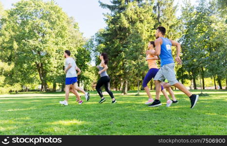 fitness, sport, race and healthy lifestyle concept - group of happy people or sportsmen running marathon with badge numbers at summer park. happy young sportsmen racing wit badge numbers