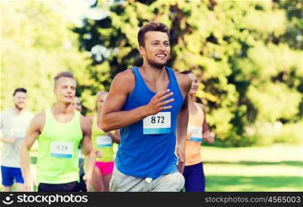 fitness, sport, race and healthy lifestyle concept - group of happy teenage friends or sportsmen running marathon with badge numbers outdoors