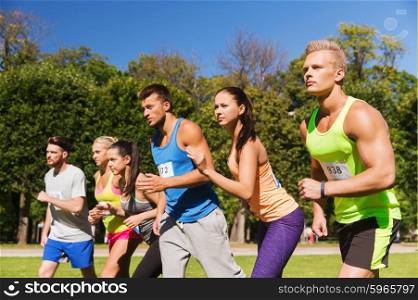fitness, sport, race and healthy lifestyle concept - group of teenage friends or sportsmen with badge numbers on start of running marathon outdoors