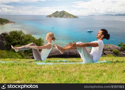 fitness, sport, relax and people concept - couple making yoga half-boat pose over natural background. couple making yoga half-boat pose outdoors