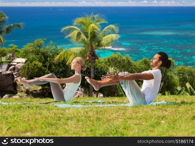 fitness, sport, relax and people concept - couple making yoga half-boat pose over natural background. couple making yoga half-boat pose outdoors