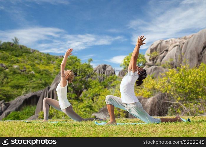 fitness, sport, relax and people concept - couple making yoga in low lunge pose over natural background. couple making yoga in low lunge pose outdoors