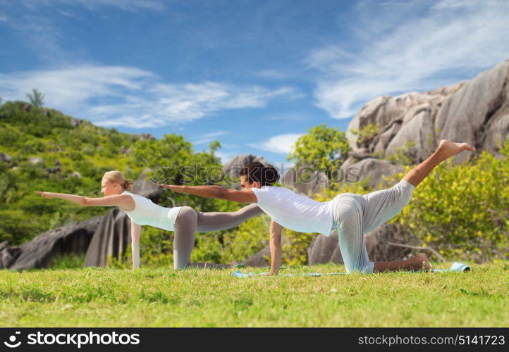 fitness, sport, relax and people concept - happy couple making yoga in balancing table pose outdoors over natural background. happy couple making yoga exercises outdoors