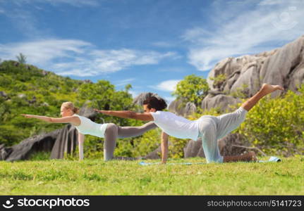 fitness, sport, relax and people concept - happy couple making yoga in balancing table pose outdoors over natural background. happy couple making yoga exercises outdoors