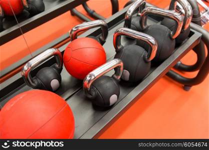 fitness, sport, sports equipment, weightlifting and bodybuilding concept - close up of kettlebells and medicine ball in gym