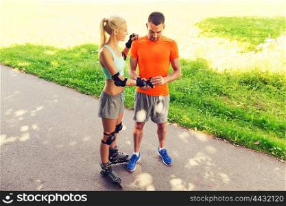 fitness, sport, summer and healthy lifestyle concept - happy couple with roller skates riding outdoors