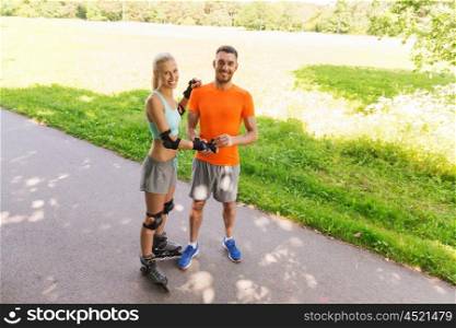fitness, sport, summer and healthy lifestyle concept - happy couple with roller skates riding outdoors