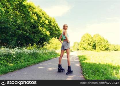 fitness, sport, summer, rollerblading and healthy lifestyle concept - happy young woman in rollerskates riding outdoors