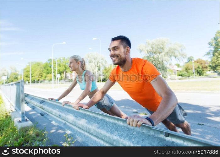 fitness, sport, training and healthy lifestyle concept - close up of happy couple doing push-ups outdoors